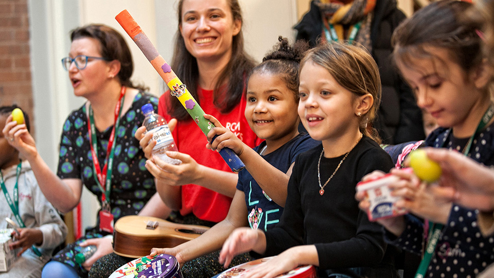 Children and adults at an RCM Sparks events, smiling and playing recycled instruments